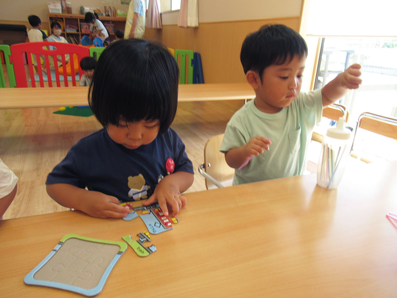 テーブルでパズルを使って遊ぶ子どもたち